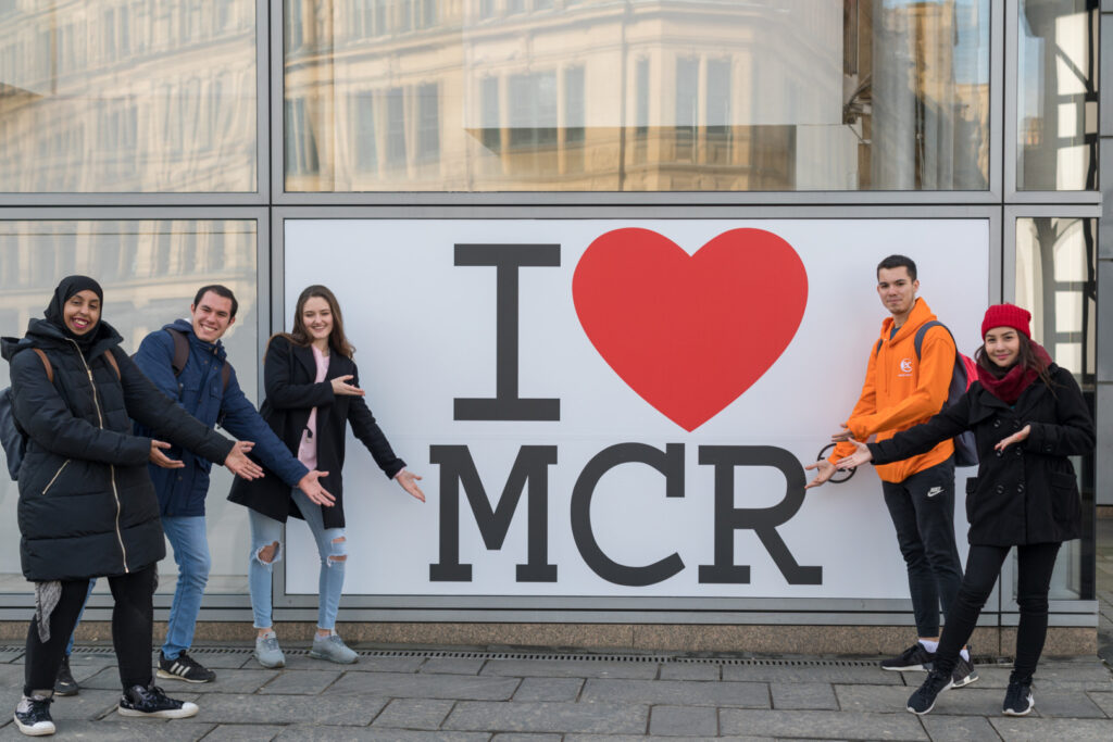 Five EC Manchester students standing beside a "I love MCR" poster.