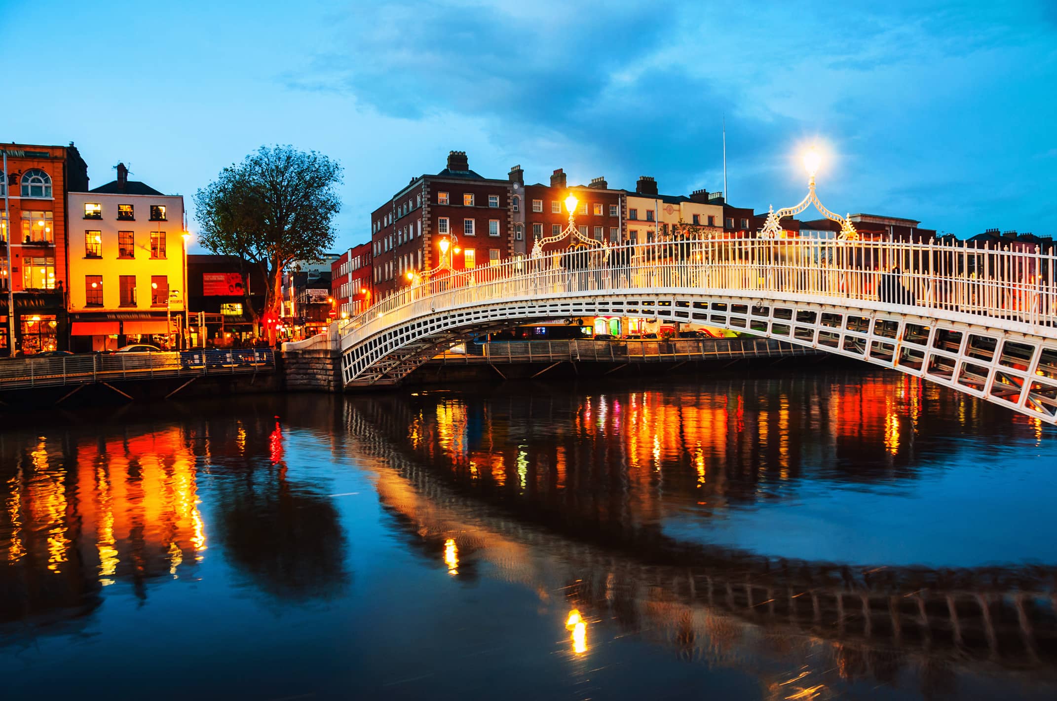 Il Ponte Ha'penny illuminato al tramonto sul fiume Liffey a Dublino, una destinazione ideale per gli studenti che imparano l'inglese con EC Dublin.