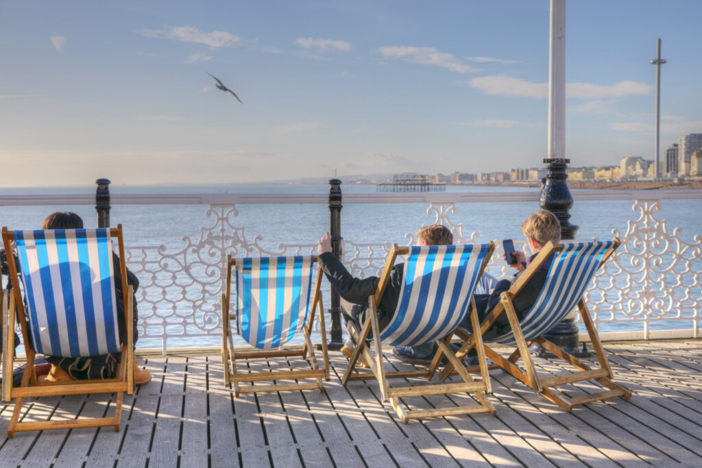 Studenti si rilassano sulle sedie a sdraio sul lungomare di Brighton durante il loro soggiorno di studio con EC English.