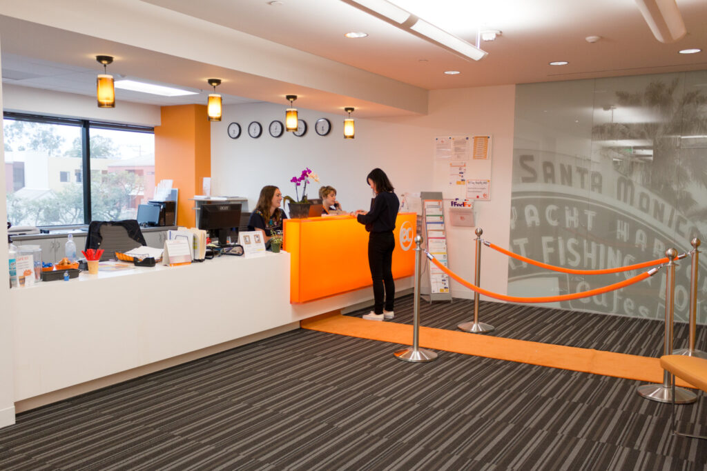Personale con uno studente al banco della reception - Scuola di inglese EC Los Angeles
