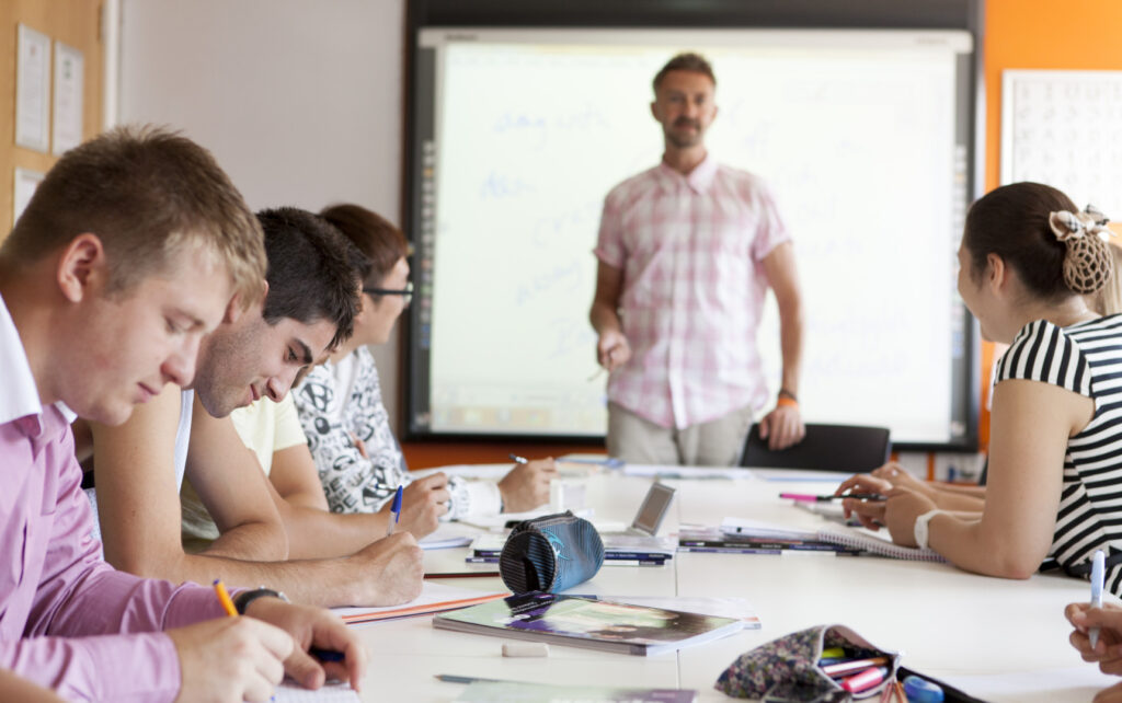 Studenti che partecipano a una lezione di inglese presso EC English mentre l'insegnante tiene la lezione davanti alla classe.