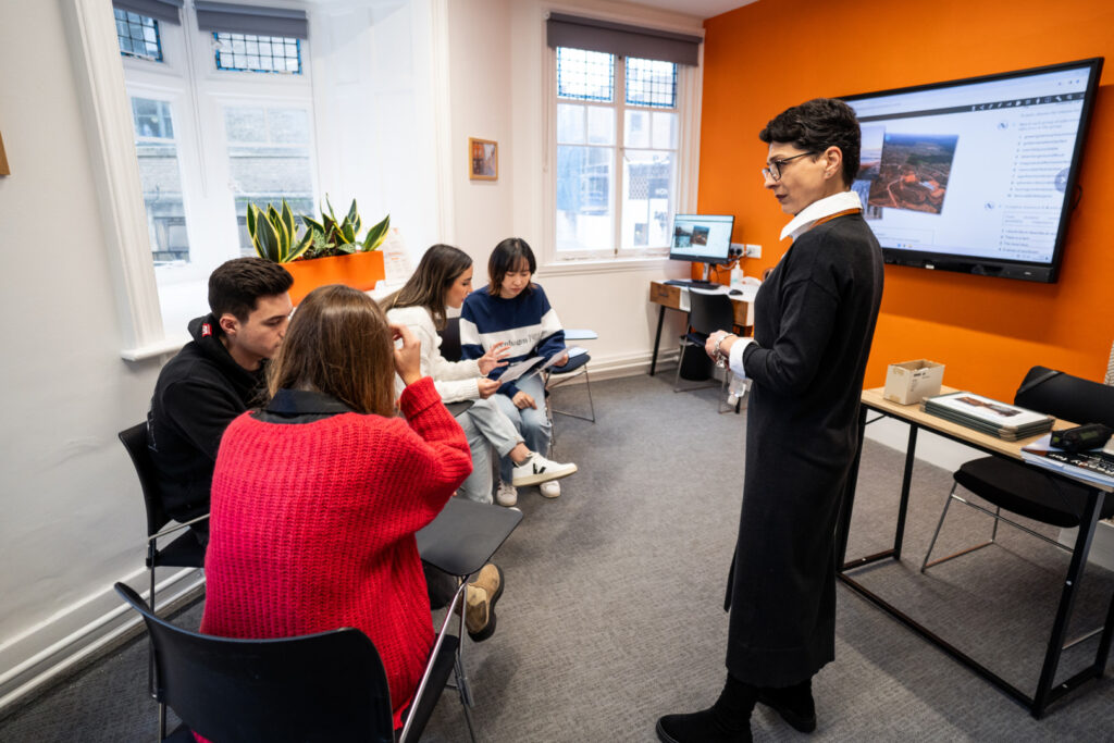 Studenti che partecipano a una lezione di inglese con un'insegnante presso EC English Cambridge in un'aula moderna.